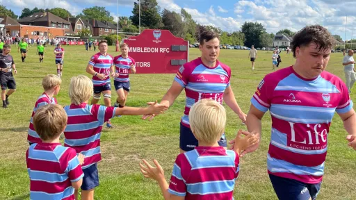 Rugby players of all ages in colorful jerseys on a sunny field.