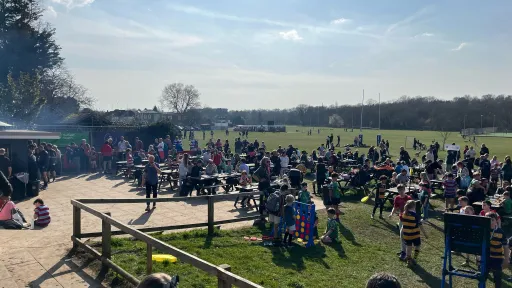 Crowd of people enjoying a sunny day at a spring rugby festival on a grassy field.