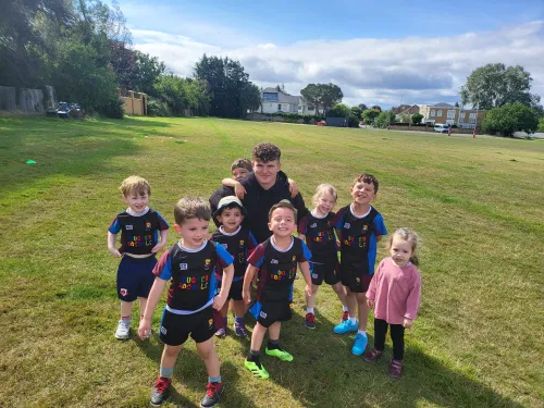 Group of children at Rugger Rhinos posing together on a grassy field.