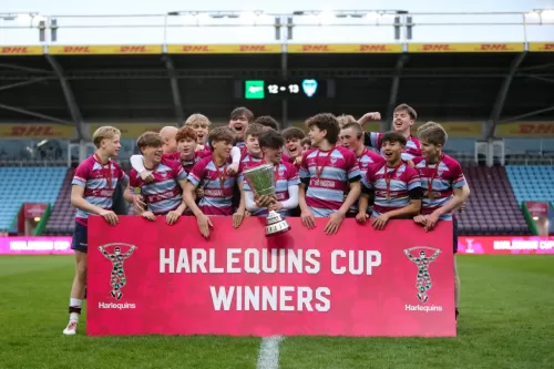 A group of young rugby players celebrating as they hold a trophy and banner reading "Harlequins Cup Winners."